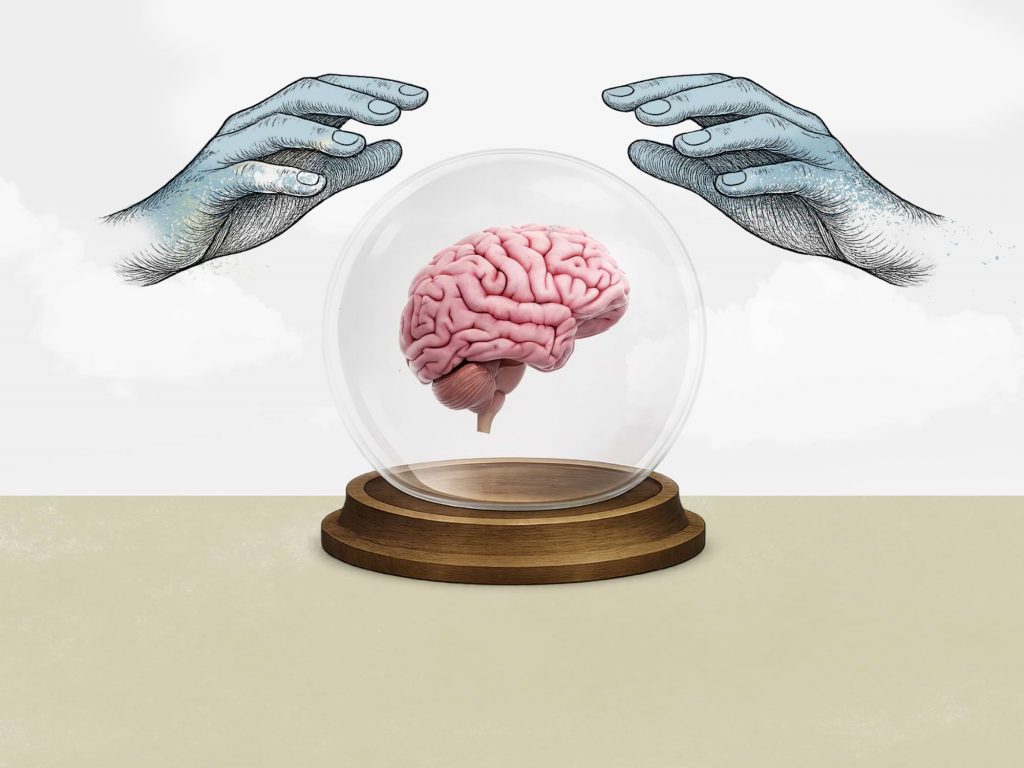 Bola de cristal con cerebro en su interior y manos grabadas alrededor, imagen conceptual sobre el proceso de naming estratégico.